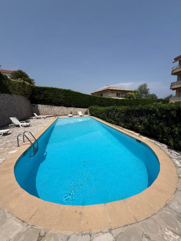 une grande piscine bleue dans une cour dans l'établissement Studio cosy avec piscine proche du bord de mer, à Villeneuve-Loubet