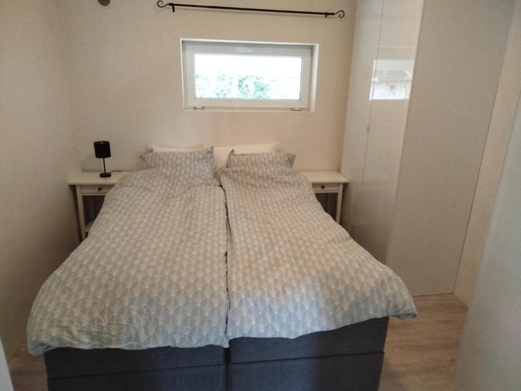 Una cama en una habitación pequeña con ventana. en Margaret's Home strandparken, en Horten