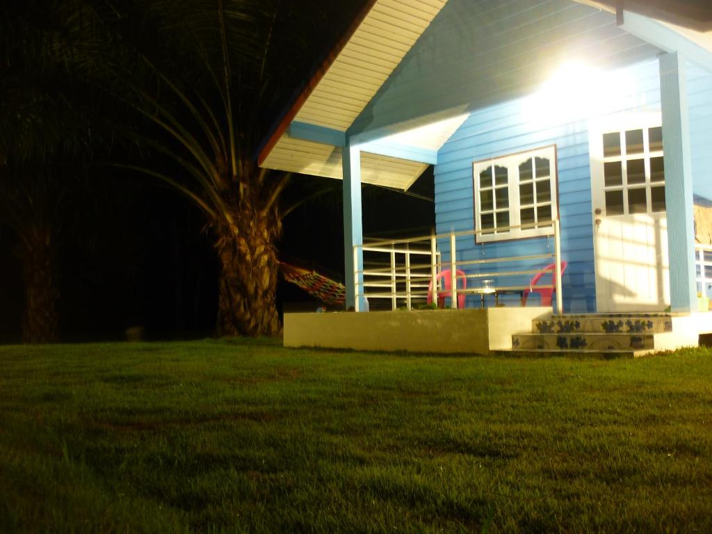 une maison bleue avec un arbre en face dans l'établissement Maneemudjalin Resorts Farm Stay, à Sam Roi Yot