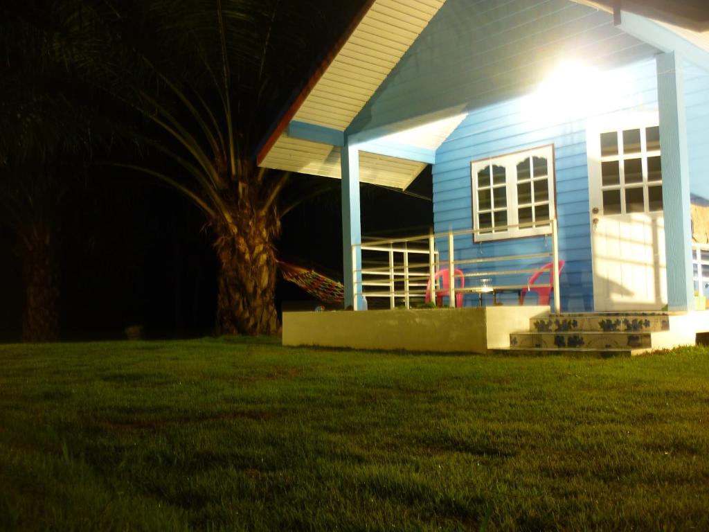 una casa azul con un árbol delante en Maneemudjalin Resorts Farm Stay, en Sam Roi Yot