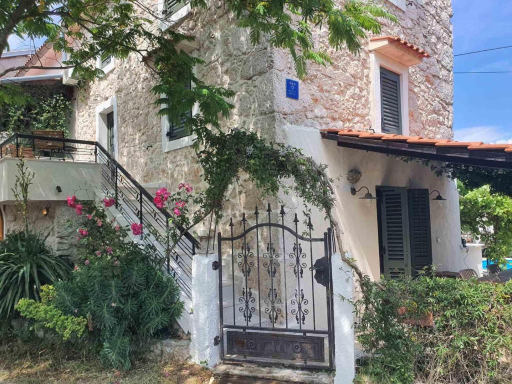 a stone house with a gate and flowers at Cosy Getaway in Gostinjac