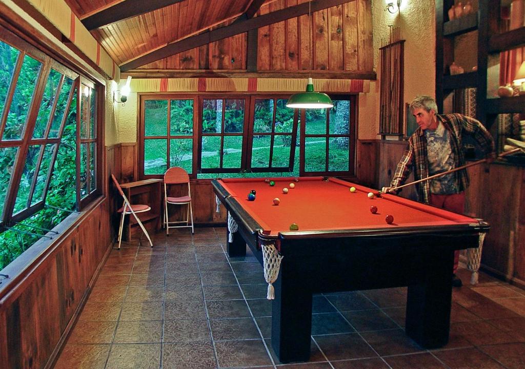 a man standing in a room with a pool table at Hotel Bühler in Visconde De Maua