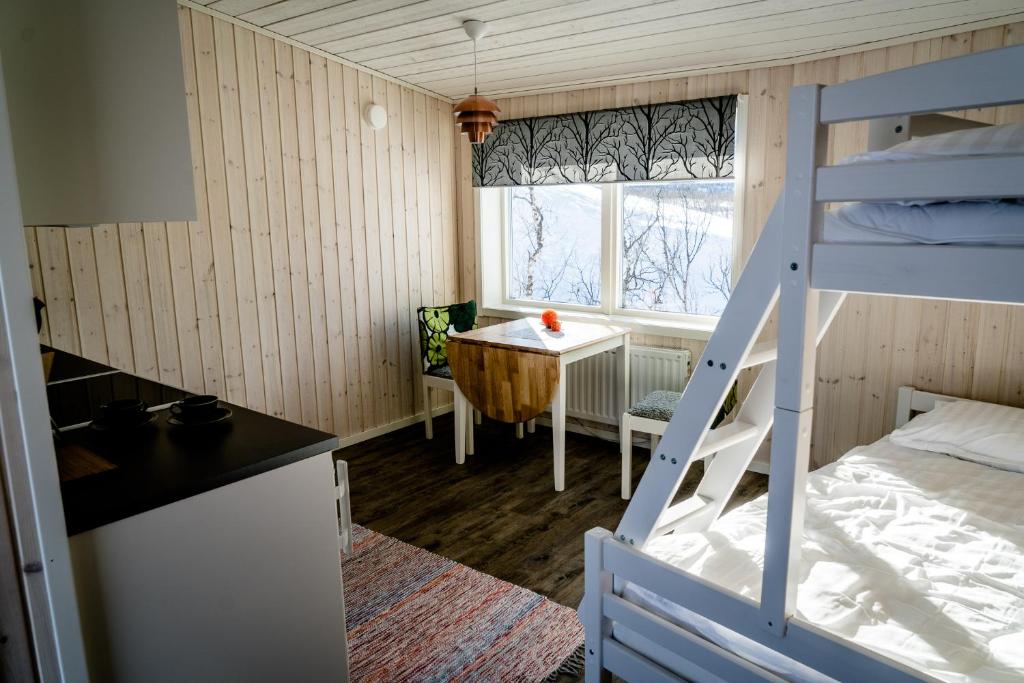 NikkaluoktaにあるEnoks i Láddjujávriの二段ベッドとテーブルが備わる小さな客室です。