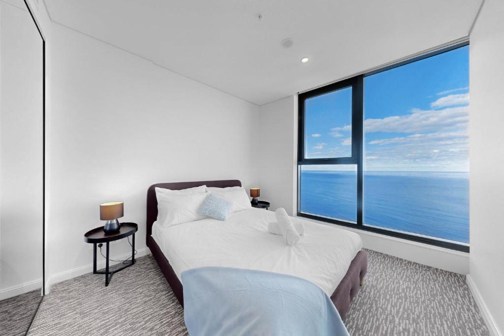 a bedroom with a bed and a large window at Beach Front 2BR Meriton Sunrise & Ocean Views in Gold Coast