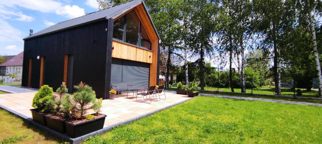 Kotlina Kłodzka Pod Brzozami في كوادسكوم: منزل أسود مع نافذة كبيرة على ساحة