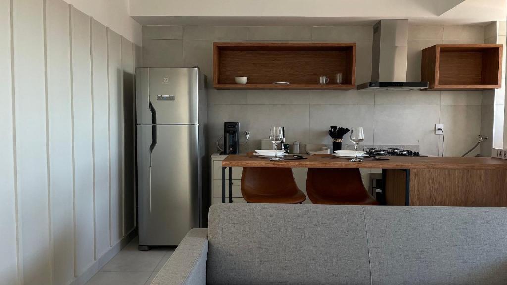 a kitchen with a refrigerator and a table with chairs at Apto com sacada gourmet e piscina – perto do centro de Bauru in Bauru