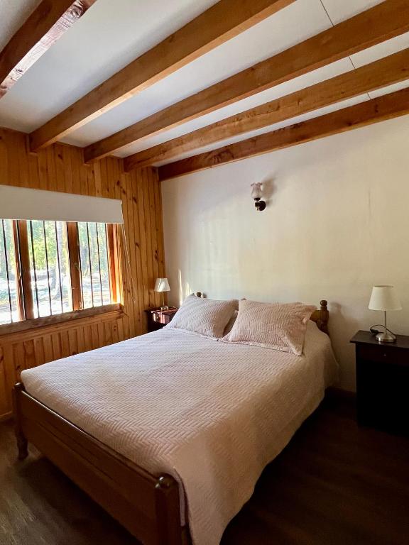 1 dormitorio con cama grande y techo de madera en Cabañas Bosque las Trancas, en Las Trancas