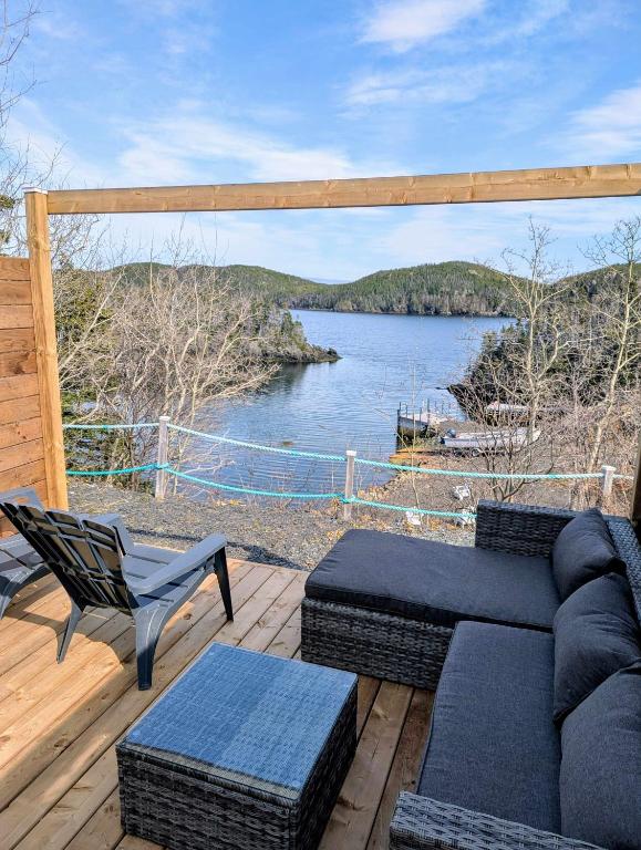 a patio with a couch and a chair and a lake at Hatchet Harbour Cottage in Herring Neck
