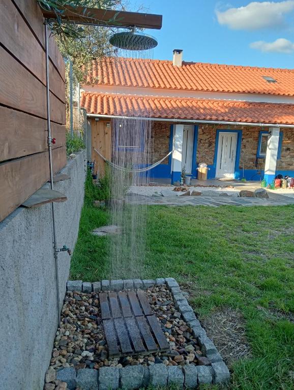 a garden with a water hose on the side of a house at Casinha das Estrelas in Cerejeira