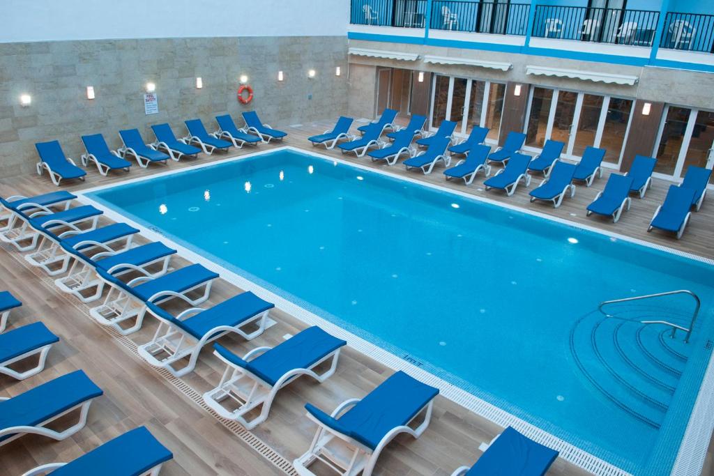 an indoor swimming pool with chairs and a pool table at Euroclub Hotel in St Paul's Bay