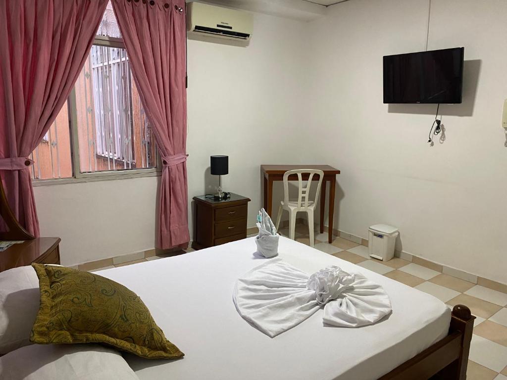 a bedroom with a bed with a television and a chair at Hotel Los Corales Tulua in Tuluá