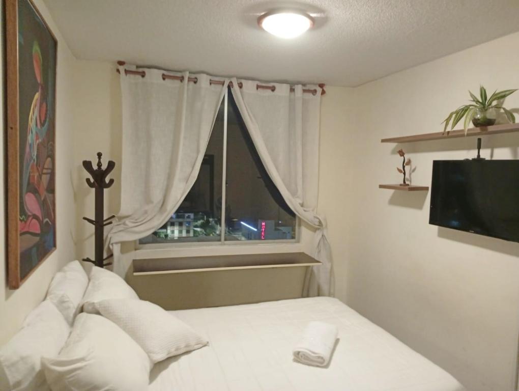 Un dormitorio con una cama blanca y una ventana. en Habitación con vista al mar, en Lima