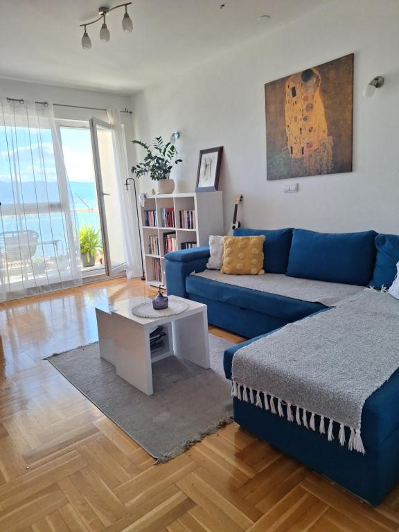 a living room with a blue couch and a table at Seaview apartman Vice in Trogir