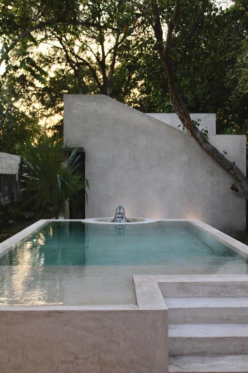 a swimming pool with a fountain in a backyard at CASA TAMA in La Ermita, Mérida Center with pool in Azcorra
