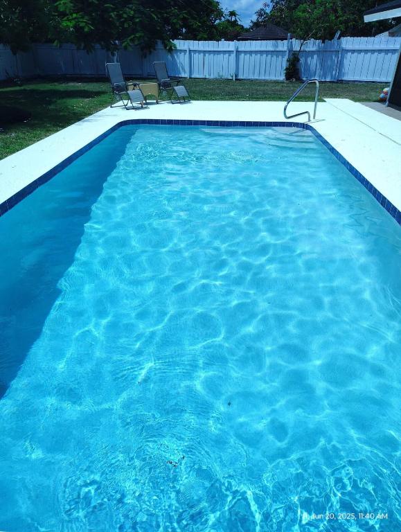 a pool of blue water with two chairs in it at Splash Oasis, 4BR, 2BA Heated Pool, BBQ in Port Saint Lucie