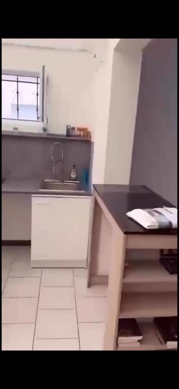 Studio 40m2 Dunkerque في دونكيرك: مطبخ مزود بمنضدة وحوض وطاولة