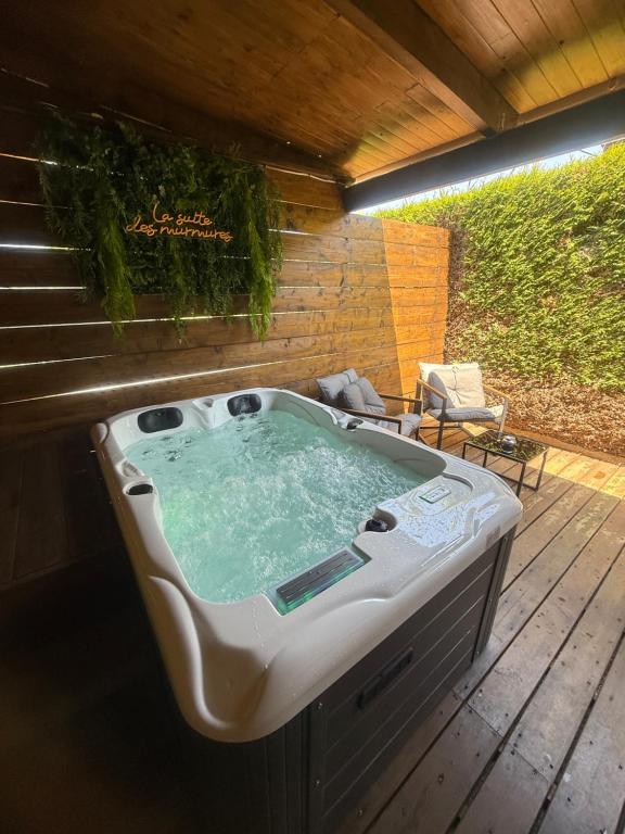 un bain à remous sur une terrasse en bois avec une chaise dans l'établissement La suite des murmures, à Scionzier