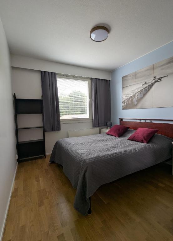 a bedroom with a large bed with two red pillows at Nice and spacious apartment in center - own carport and private sauna in Rauma
