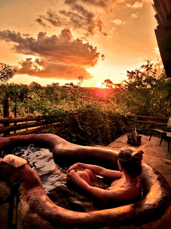 a woman sitting in a bath tub with the sunset at BioChalé Buena Vista in Sao Jorge