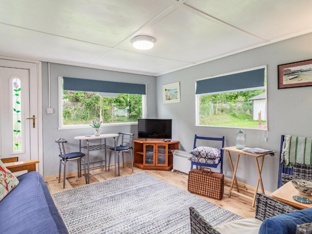 a living room with a blue couch and two windows at Bluebird Chalet - Uk38524 in Mundesley