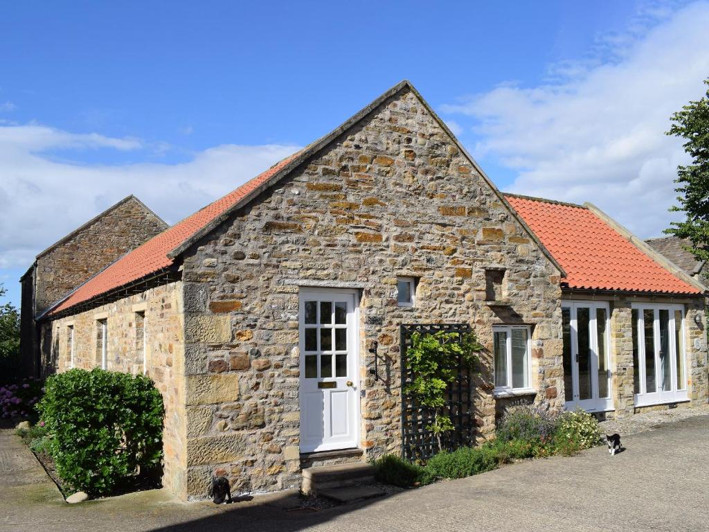 an old stone house with a red roof at Grange Cottage in Winston
