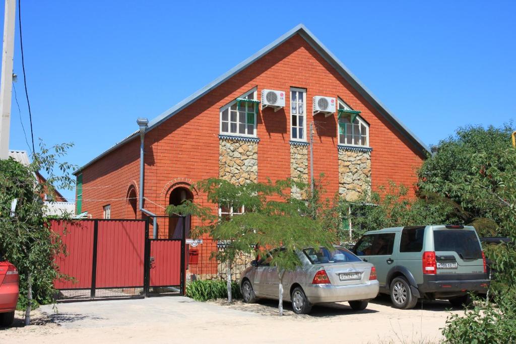 a red brick church with two cars parked in front at Solnechniy Dvorik in Golubitskaya