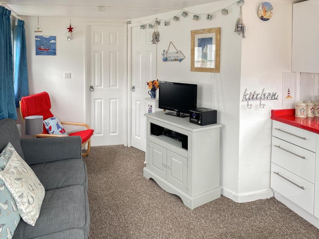 a living room with a couch and a tv on a stand at Driftwood in Mundesley