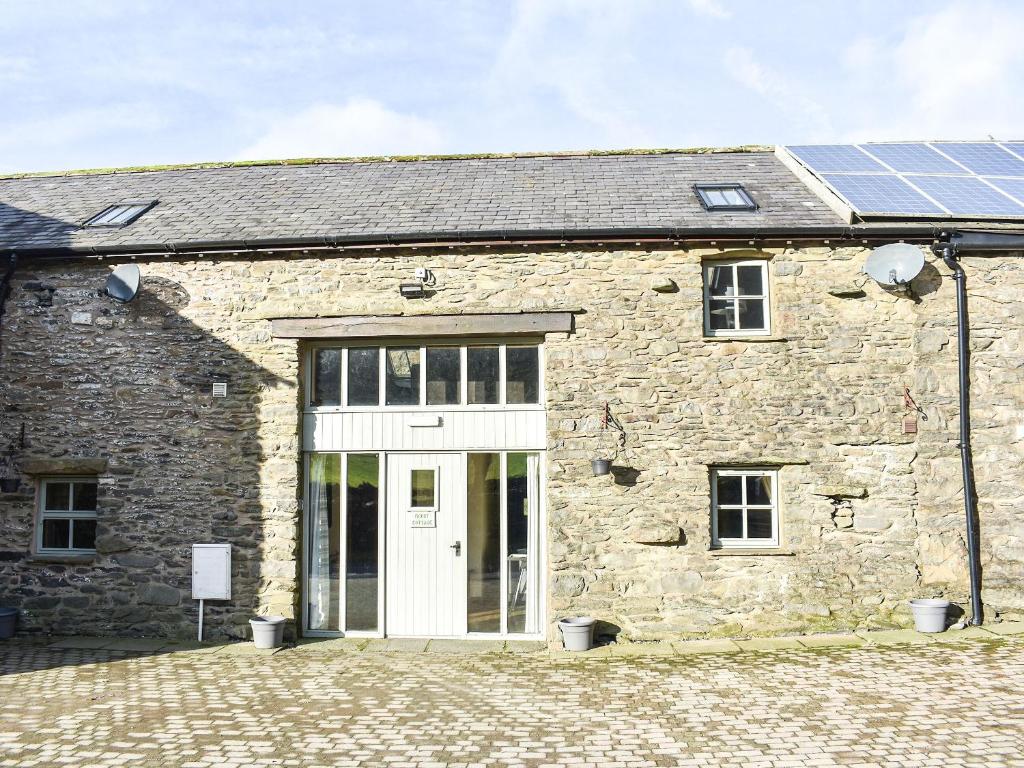 un bâtiment en pierre avec une porte blanche et un toit solaire dans l'établissement Mount Cottage-Uk42230, à Low Borrowbridge