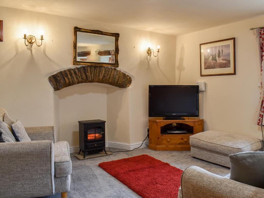 een woonkamer met een tv en een open haard bij Beck Foot Cottage in Sedbergh