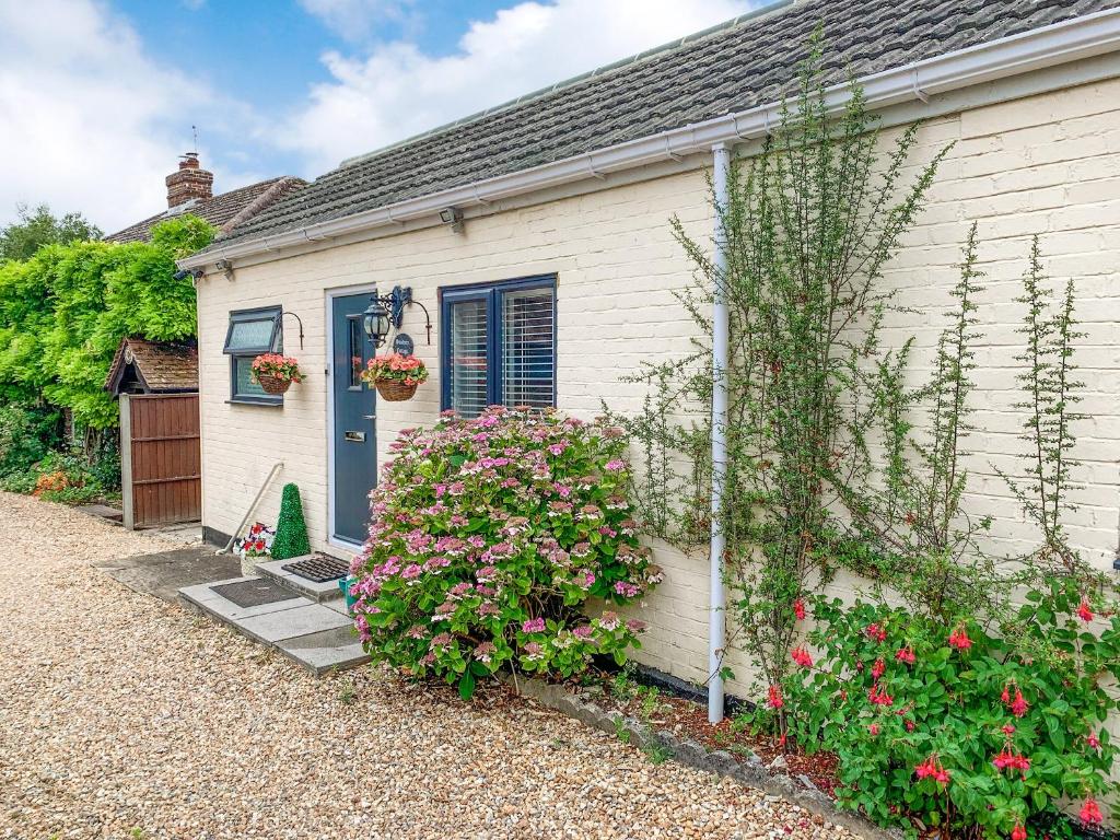 Sunbury Cottage في Clanfield: بيت ابيض بباب ازرق وبعض الزهور