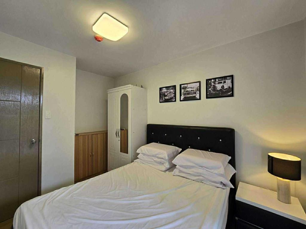 a bedroom with a bed with white sheets and pillows at 2BR FAMILY AFFORD STAYCATION TAGAYTAy in Tagaytay