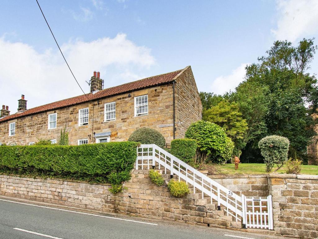 une vieille maison en briques avec une clôture blanche dans l'établissement Castle Cottage, à Castleton