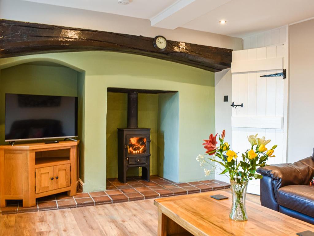 a living room with a fireplace and a tv at Wallthwaite Cottage in Threlkeld