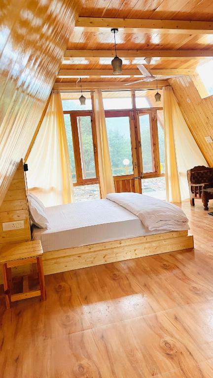 a bedroom with a bed in a room with windows at River Nest Cottage Shangarh in Sainj