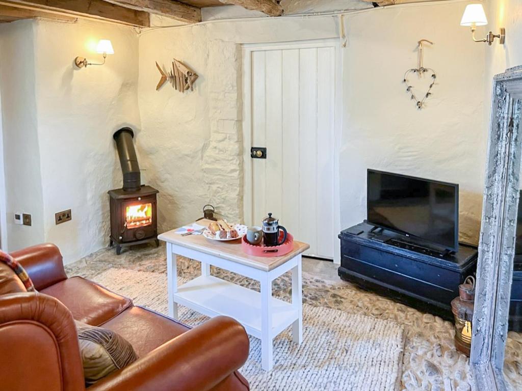 a living room with a couch and a tv and a fireplace at Cobble Cottage in Instow