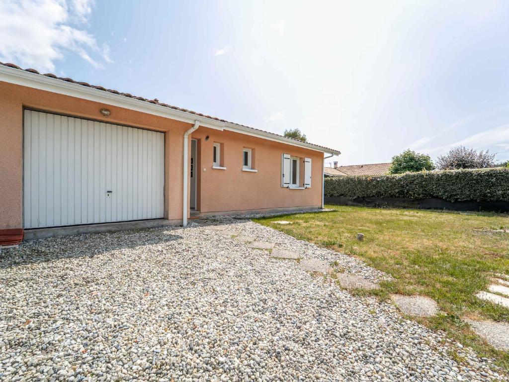 une maison avec deux portes de garage et une allée en gravier dans l'établissement Maison à Bias 6 pers – Confort et nature proche océan - FR-1-50-184, à Bias