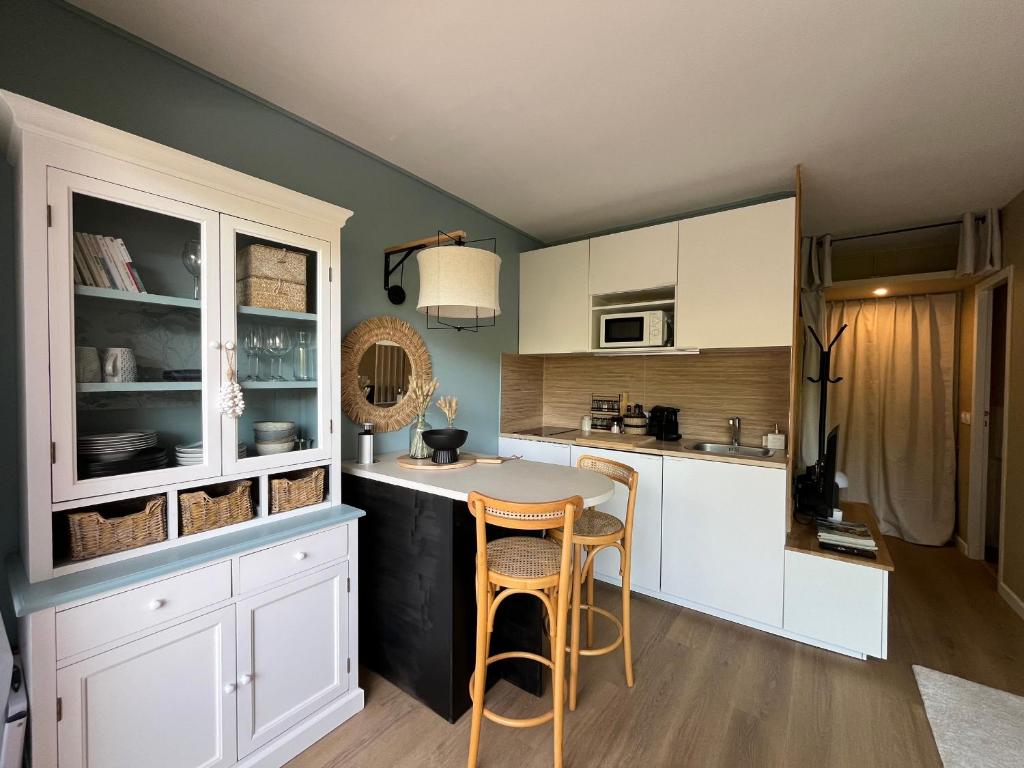 une cuisine avec des armoires blanches et une table et des chaises dans l'établissement Studio cosy à Arcachon avec parking, proche plage - FR-1-319-619, à Arcachon