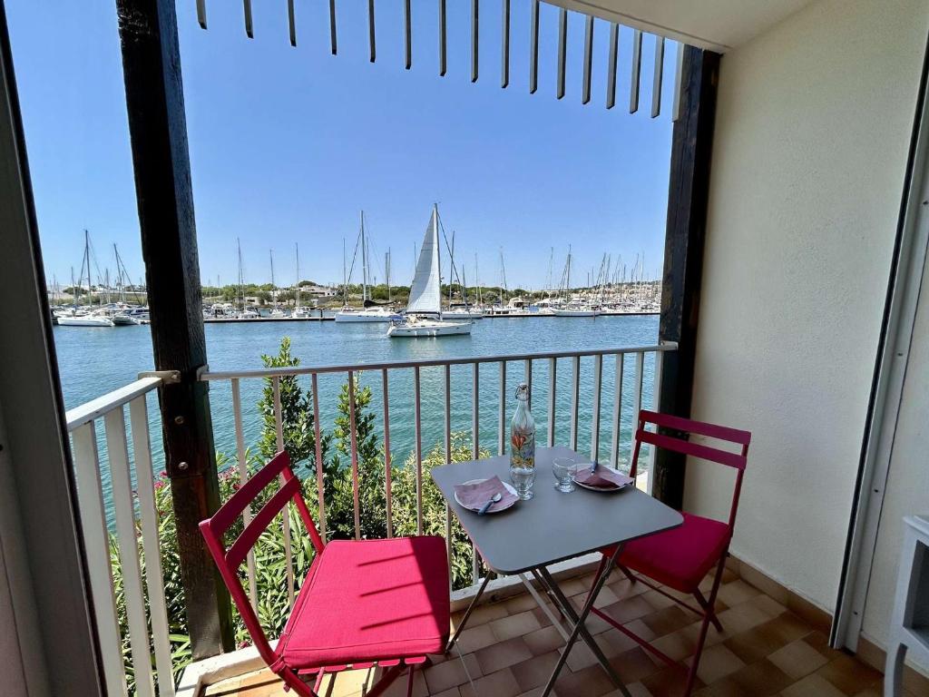un balcon avec une table et deux chaises et un voilier dans l'établissement Appartement T2 rénové, 4 couchages, vue port, Cap d'Agde - FR-1-249-446, au Cap d'Agde