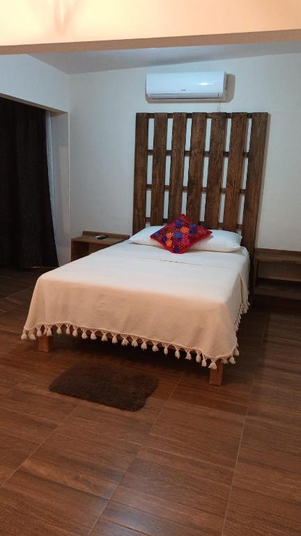 a bedroom with a large bed with a wooden headboard at Hotel Cassaterra in Ciudad Valles