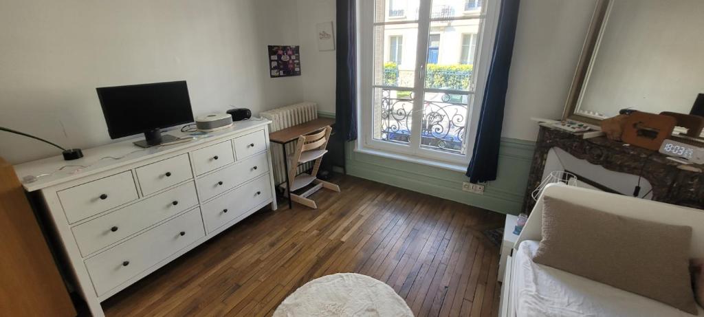 a living room with a white dresser with a television on it at Le Fiacre in Nancy