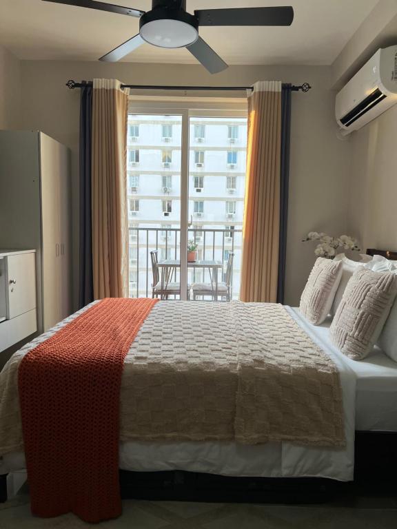 a bedroom with a bed and a large window at Studio Condo in Saekyung Village One Phase3 in Lapu Lapu City