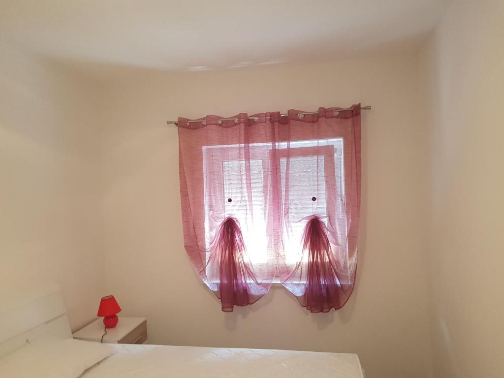 a bedroom with a window with a pink curtain at Apartments Tereza in Senj