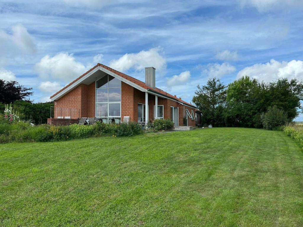 ein Backsteinhaus mit einem großen Rasen davor in der Unterkunft Summer House With Panoramic View Near Doverodde in Doverodde