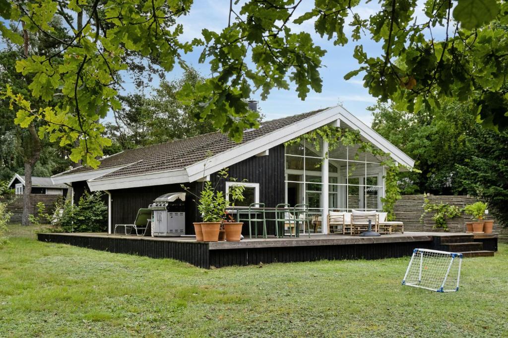 una casa pequeña con terraza y casa en Summer House Near Hornbæk Beach, en Hornbæk