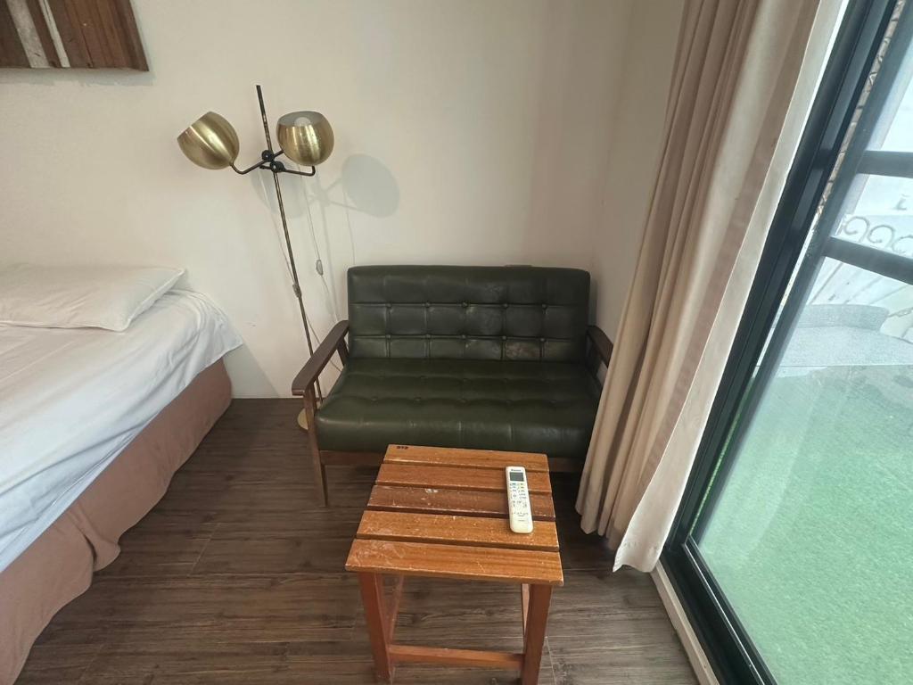a room with a couch and a table and a chair at Hour Roots in Tainan