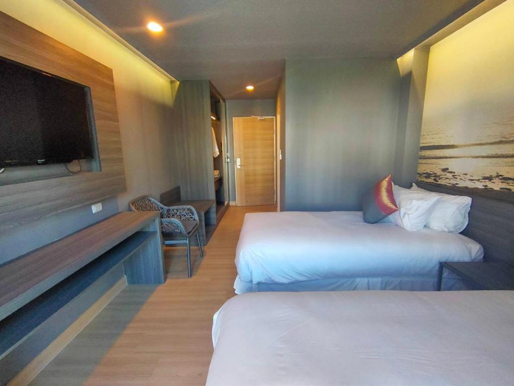 a hotel room with two beds and a flat screen tv at AD Resort Cha-am Hua Hin in Hua Hin