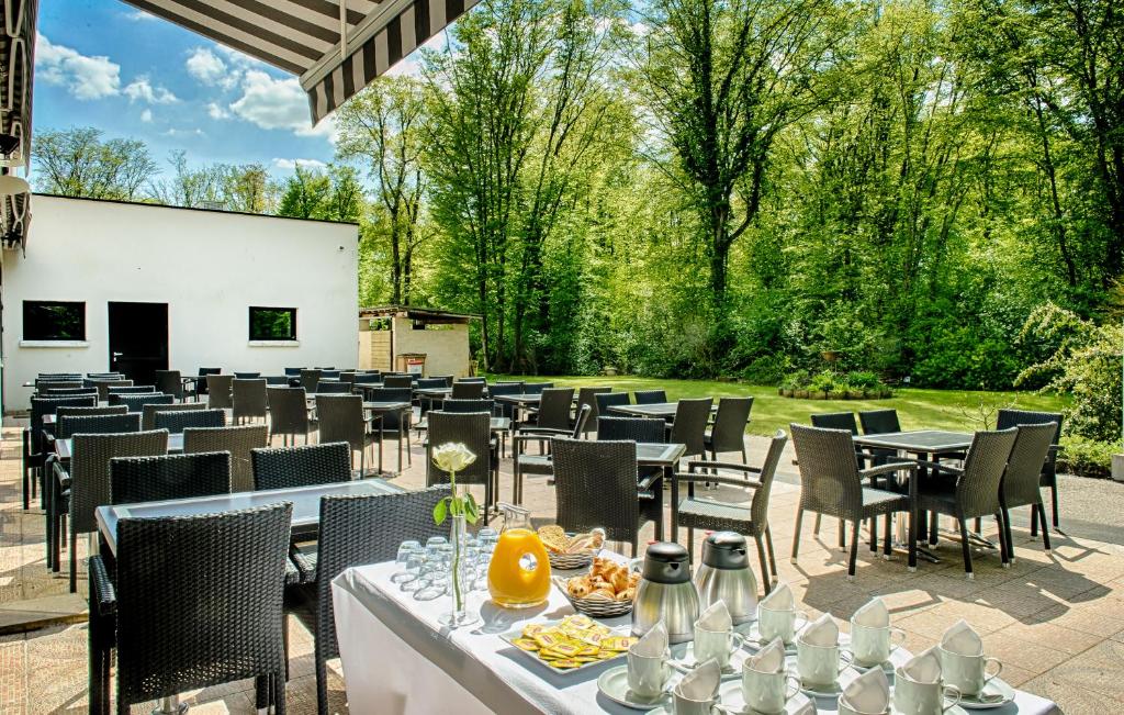 - un coin repas avec des tables, des chaises et des arbres dans l'établissement Hôtel Marso, à Amnéville
