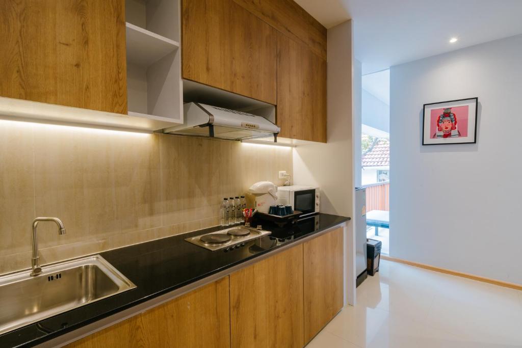 A compact kitchenette with wood cabinetry, a sink, hob, microwave, and coffee equipment.