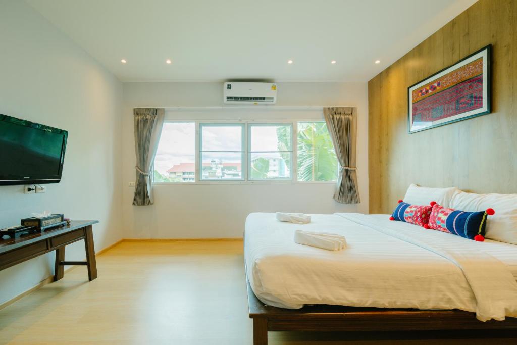 A bright bedroom with a large bed, wall-mounted television and window.