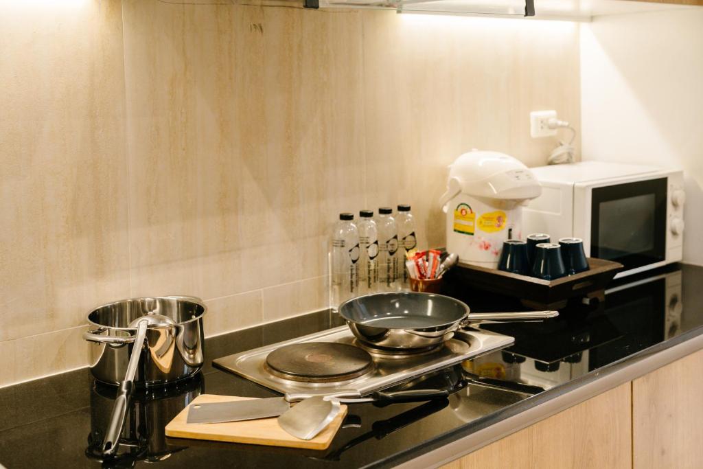 A kitchenette counter equipped with a hob, frying pan, microwave and hot-drink supplies.